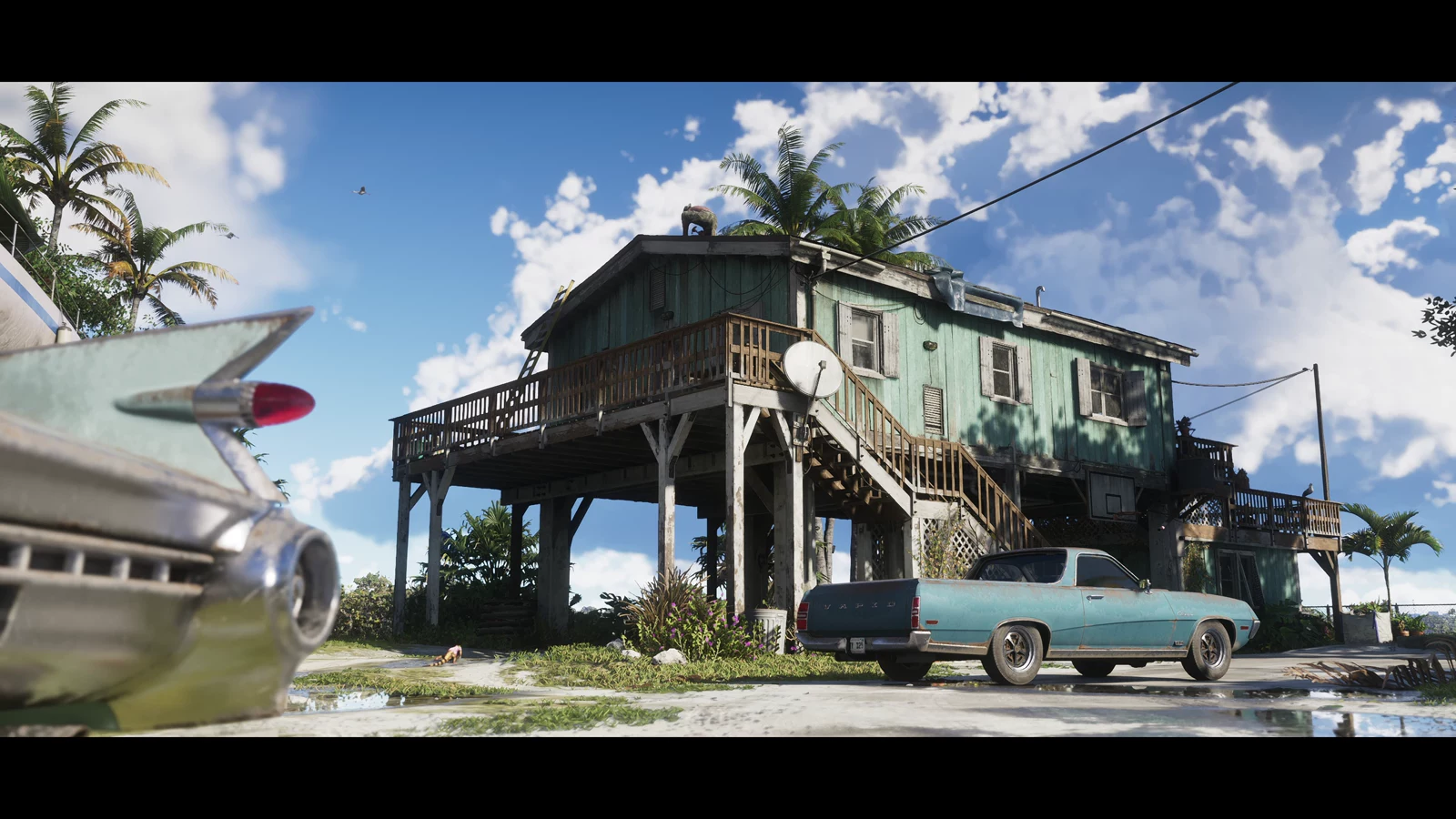 A weathered house raised on stilts beside palms and older vehicles in GTA VI Trailer 2