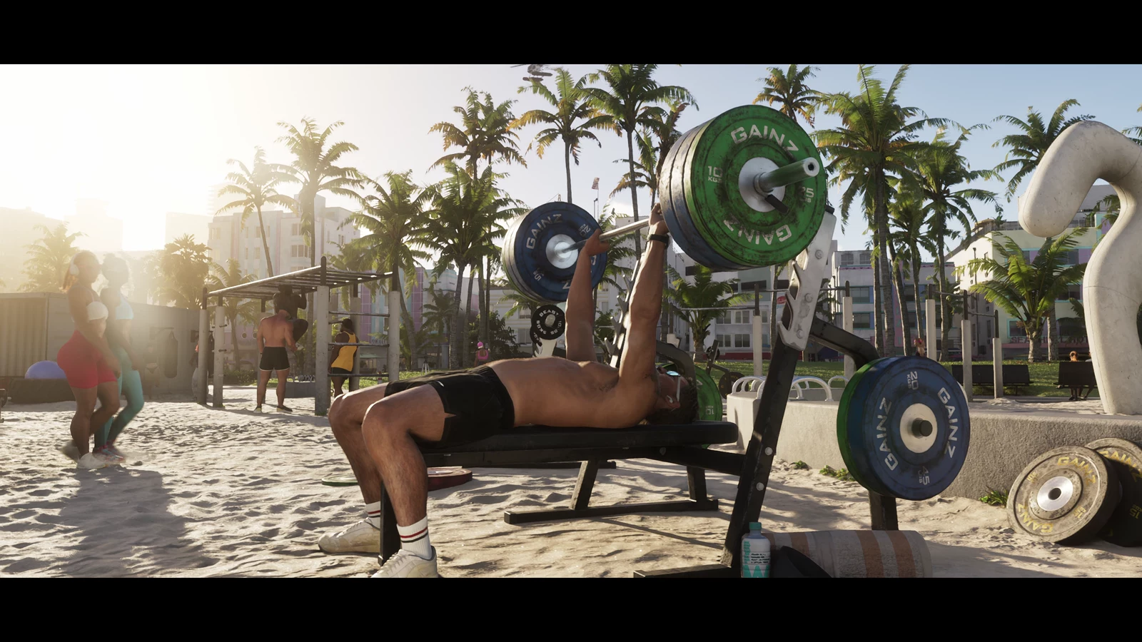 An outdoor gym on sand in front of palms and Art Deco buildings in GTA VI Trailer 2