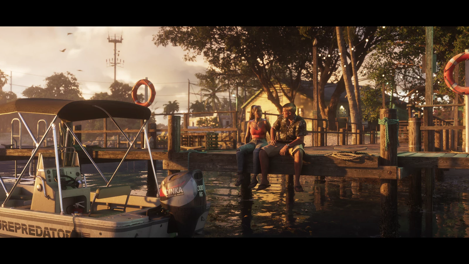 Jason and Lucia sitting on a timber marina beside a small boat at sunset